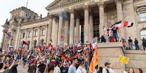 Das Reichstagsgebäude und davor Demonstranten mir Reichsflaggen