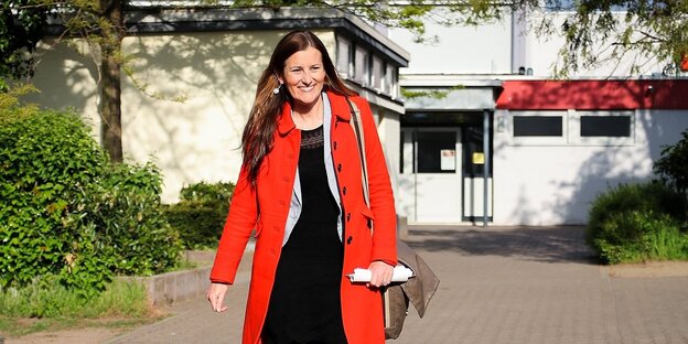 Janine Wissler mit rotem Mantel vor der Dreieichschule Langen
