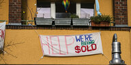 Ein Banner an dem Balkon eines Mietshauses. Drauf steht: "Help! We're being sold"