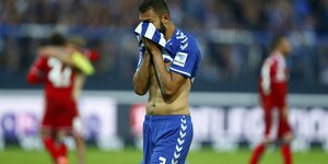 Ein Fußballspieler aus Karlsruhe hält sich das Trikot vor das Gesicht
