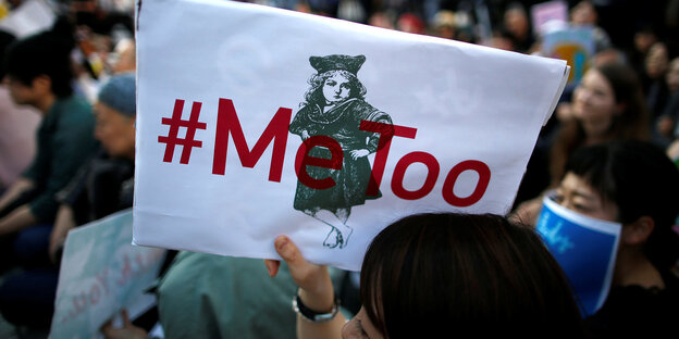 Eine Demonstrantinhält einSchild in die Luft. Darauf steht geschrieben: #MeToo. Hinter der Schrift eine Zeichnung eines Mädchens in Kleid.