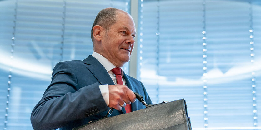 Olaf Scholz trägt eine Aktentasche