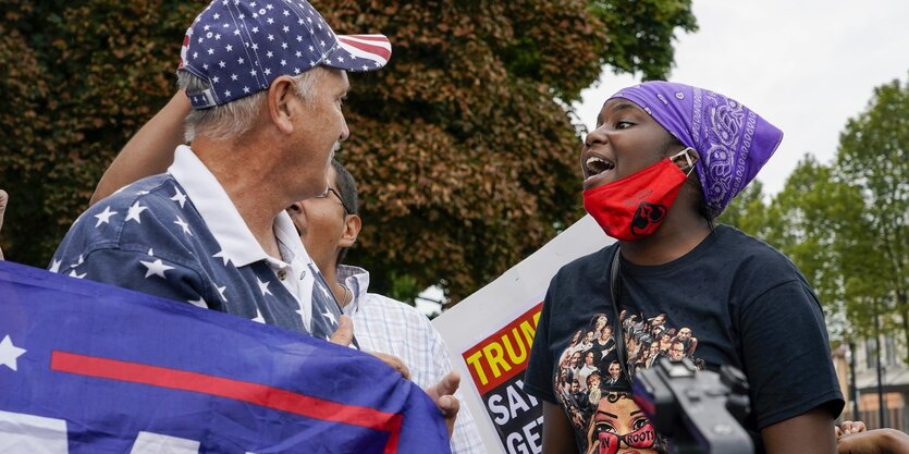 Ein weißer Trumpanhänger und eine schwarze Frau, die zu ihm spricht