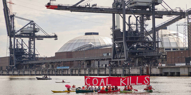 Auf der Elbe vor dem Kraftwerk Moorburg halten Aktivisten in Kanus ein Transparent "Coal Kills" hoch