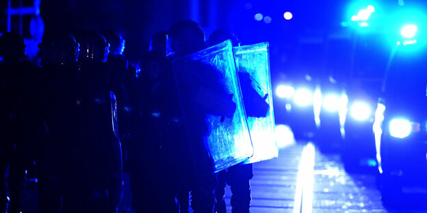 Polizisten in Schutzausrüstung mit Schutzschilden laufen am Rande einer Demonstration im Stadtteil Connewitz.