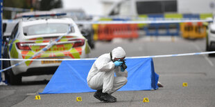 Ein Mitarbeiter der Spurensicherung in Schutzkleidung fotografiert an einem Tatort in der Irving Street.