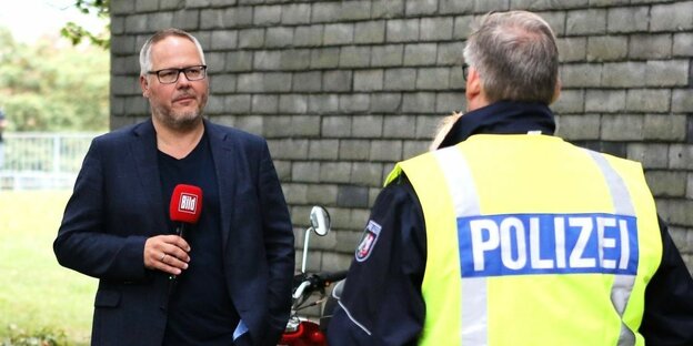 Reporter und Kameramann im Gespräch mit einem Presseprecher der Polizei