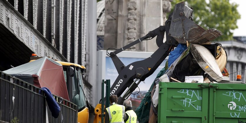 Ein Bagger räumt Zelte von Migranten in einen Müllcontainer