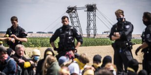 Polizisten halten eine Gruppe am Boden sitzende Demonstranten in Schach
