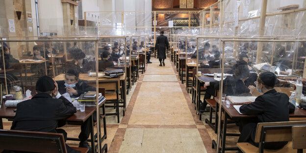 27.08.2020, Israel, Bnei Brak: Ultra-orthodoxe jüdische Studenten lesen Texte in einer Jeschiwah, einem jüdischen Priesterseminar, unter Verwendung von Trennwänden aus Plastik.