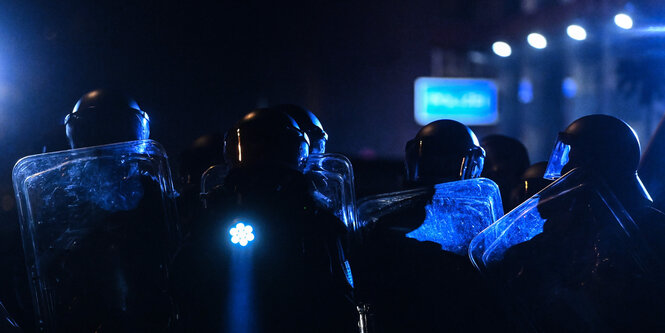 Polizisten in Schutzausrüstung mit Schutzschilden stehen am Rande einer Demonstration im Leipziger Stadtteil Connewitz