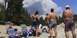 Urlauber gucken auf einen Waldbrand