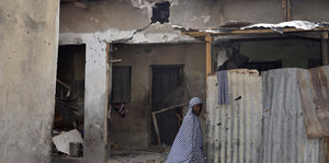 Eine Frau geht an einem beschädigten Haus vorbei