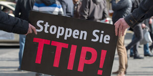 Demonstranten mit Schild, auf dem "Stoppen Sie TTIP!" steht