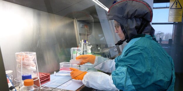 Eine Person arbeitet in grüner Schutzkleidung in Labor