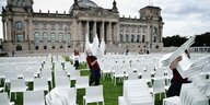 Menschen stellen Stühle vor dem Reichstag auf