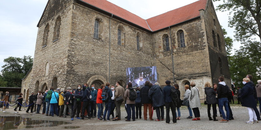 Vor einer alten Kirche bilden Menschen eine Schlange