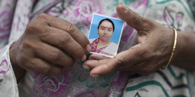 Eine Frau hält das Bild ihrer verstorbenen Tochter in die Kamera