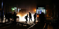 Demonstranten sind nachts auf einer Straße in Leipzig, im Hintergrund Straßenbahnen