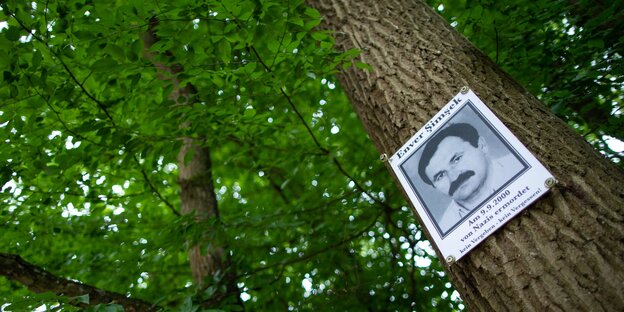 Ein Foto des vom NSU ermordeten Enver Simsek hängt an einem Baum