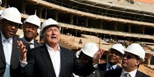 Sepp Blatter und andere Fußballfunktionäre mit Helmen in neugebautem Stadion nahe Soweto