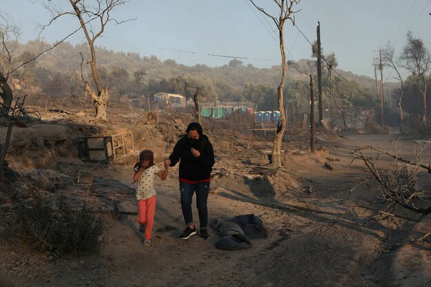 Eine Frau hält ein Kind an der Hand, sie laufen durch eine ausgebrannte Landschaft