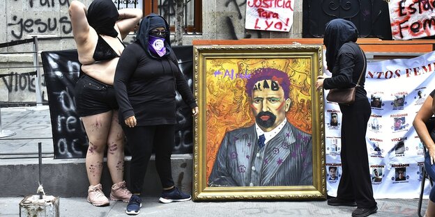 Frauen stehen neben einem Gemälde, das mit Graffittis bemalt ist