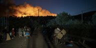 Menschen fliehen vor einem im Hintergrund brennenden Feuer