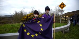Zwei Jungen stehen mit einer EU-Fahne am Straßenrand