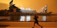 San Francisco: Ein Mann joggt bei verdunkeltem Himmel entlang der McCovey Cove vor dem Oracle Park Stadion. Die Menschen von San Francisco bis Seattle erwachten am Mittwoch mit dunstigen Rauchwolken von den Waldbränden in der Luft, die den Himmel in einem