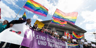 TeilnehmerInnen einer Demo mit Regenbogenfahnen und ein Transparent mit der Aufschrift: "Wir sind gegen Homophobie und Transphobie"