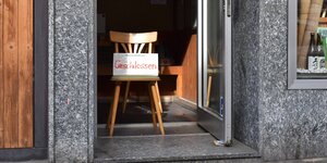 Ein Stuhl steht in einem Türrahmen, darauf ein SChild mit der Aufschrift "Geschlossen"