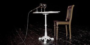 Ein weißer Tisch steht auf einer Bühne, darauf stehen zwei Wassergläser