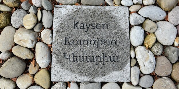 Ein eckiger grauer Gedenkstein liegt inmitten runder Kieselsteine. Darauf steht Kayseri: der Name eines der Herkunftsorte der Opfer des Genozids in der Türkei.