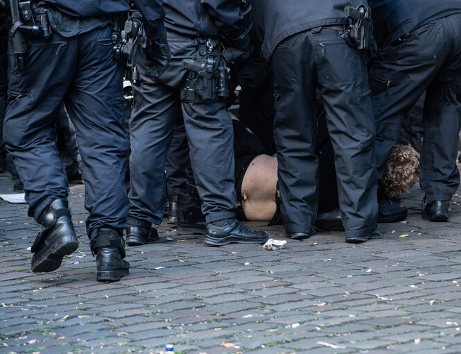 Ein mann liegt auf dem Boden, viele Polizisten stehen um ihn herum