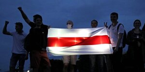 Menschen im Dunkeln mit der Fahne der Opposition in Belarus, die leuchtet