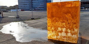 Ein orangefarben bemalter Eisblock schmilzt im Sonnenschein