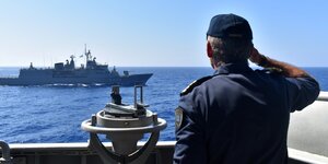 Griechischer Marinesoldat salutiert vorbeifahrendem Kriegsschiff