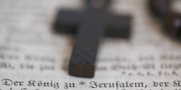 Ein Holzkreuz liegt auf einer Bibelseite
