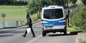 Ein vermummter Polizist geht während einer Durchsuchung zu einem Grundstück bei Neubrandenburg