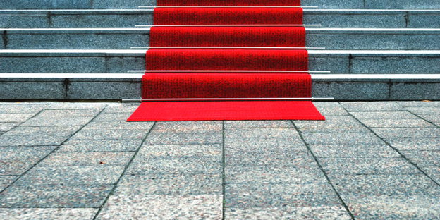 Ein roter Teppich liegt auf einer grauen Treppe.