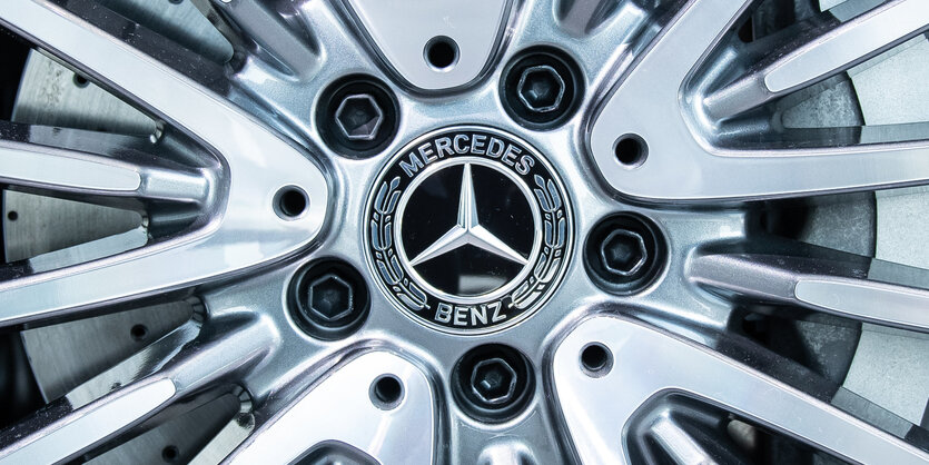 Das Logo des Autoherstellers Daimler. Im Vordergrund der Teil einer Autofront