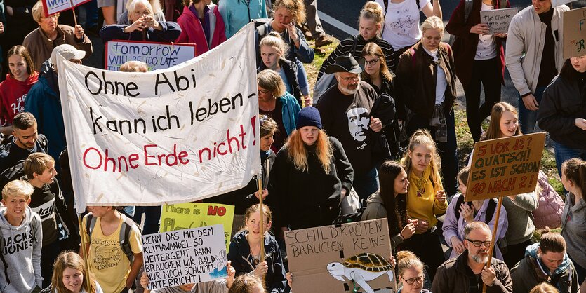 Junge Menschen demonstrieren mit Schildern und Plakaten gegen die Klimapolitik.