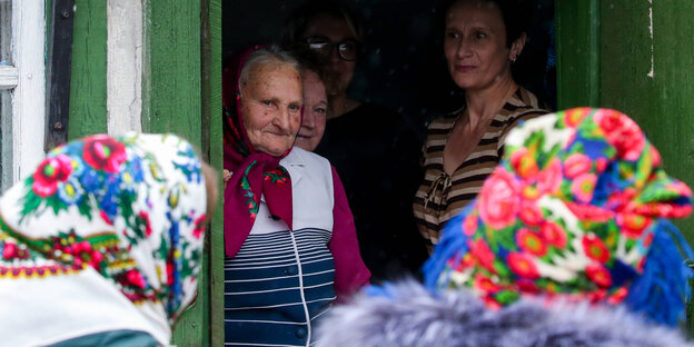 Eine alte Frau auf einem Dorf in Belarus schaut aus der Tür ihres Hauses