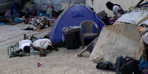 Menschen schlafen vor einem Zelt