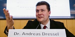 Andreas Dressel sitzt und gestikuliert hinter seinem Namensschild.