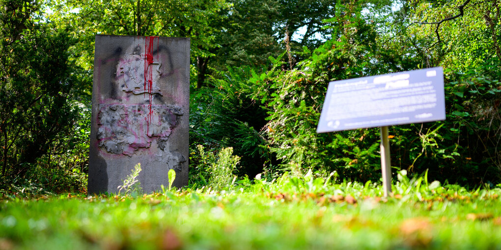 Der Gedenkstein für die 110. Infanterie-Division der Wehrmacht steht mit Beton unkenntlich gemacht und beschmiert in einer Grünanlage in Lübeck.