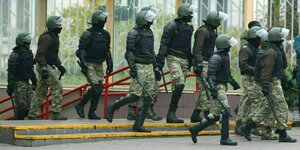 Belarusische Polizeibeamte in Tarnfleck und mit Schlagstöcken in der Hand sind auf dem Weg