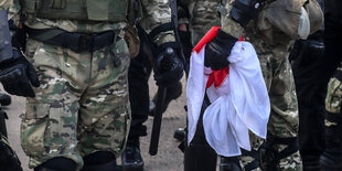 Sicherheitskräfte halten eine rot-weiße Flagge, die während eines Protests von Anhängern der Opposition in Minsk von Demonstranten beschlagnahmt wurde