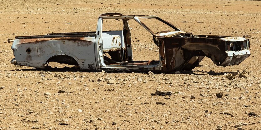 Ein verlassenes Autowrack steht ohne Räder in der Wüste